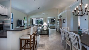A spacious kitchen with a central island, a dining area with a chandelier, and a ceiling fan. - Naples Luxury Spotless 4 Bdrm Heated Pool Walk Bike To Beach  (Naples)