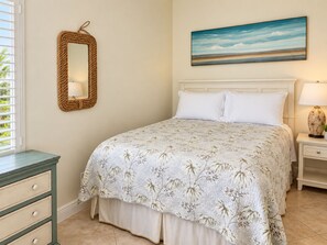 A bedroom with a bed, a nightstand, a lamp, a mirror, and a painting on the wall.