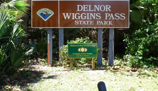 Een bord voor Delnor Wiggins Pass State Park met een Florida Park Service embleem.