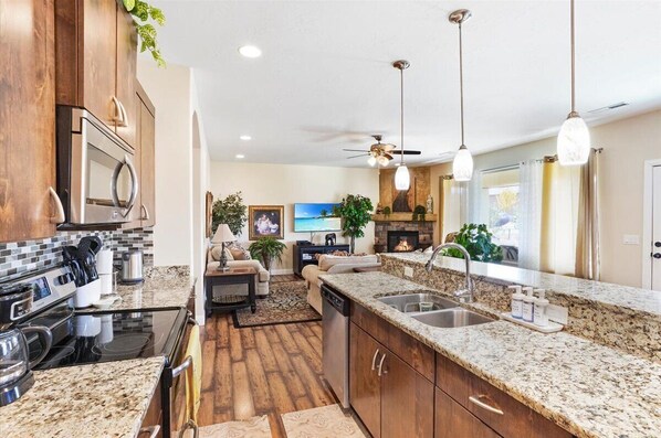 A modern kitchen with granite countertops, stainless steel appliances, and a built-in microwave.