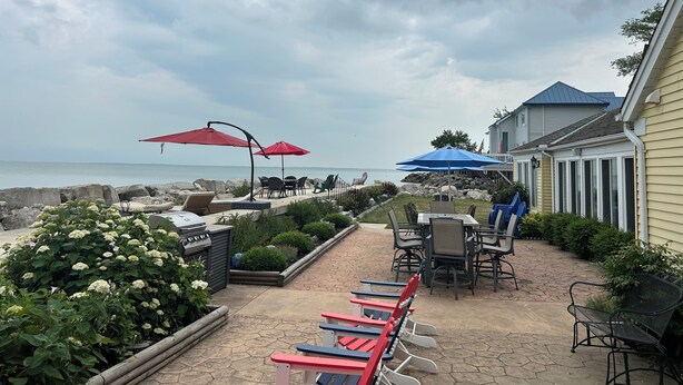 Een terras met buitenmeubilair, een barbecue en uitzicht op zee.