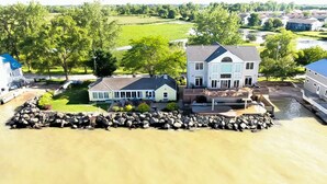 Een huis met een steiger die uitsteekt in het water, omgeven door een stenen muur en begroeiing.