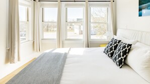 Un dormitorio con una cama grande, varias ventanas y vistas al exterior.