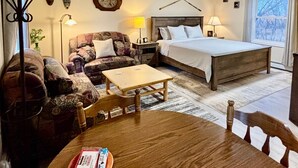 A cozy room with a bed, a sofa, a small table, and a window with a view.