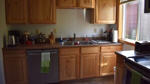 A kitchen with wooden cabinets, stainless steel appliances, and a window providing natural light. - 1 Block From The Beach! (Seward)