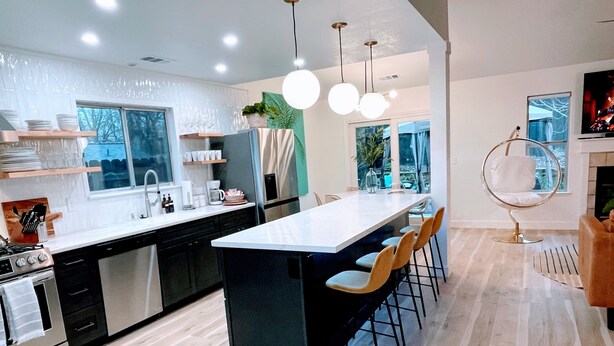A modern kitchen with a central island, bar stools, and pendant lighting. - Emerald House - striking, remodel in tranquil, central neighborhood (Redding)