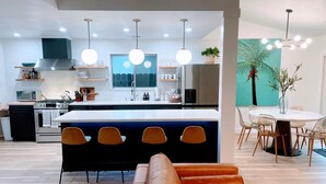 A modern kitchen with a central island, stainless steel appliances, and pendant lighting. - Emerald House - striking, remodel in tranquil, central neighborhood (Redding)
