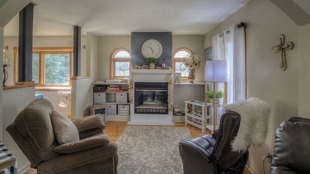 A cozy living room with a fireplace, two armchairs, a bookshelf, and a large window. - Downtown Custer &  neighbor to Rock Crest Lodge (Custer)