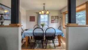 A dining room with a table set for four, a chandelier, and a window with a view of trees. - Downtown Custer &  neighbor to Rock Crest Lodge (Custer)