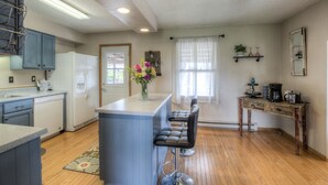 A compact kitchen with a central island, bar stools, a refrigerator, and a coffee station. - Downtown Custer &  neighbor to Rock Crest Lodge (Custer)