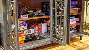 Quarto com um grande armário de madeira cheio de jogos e quebra-cabeças diversos.