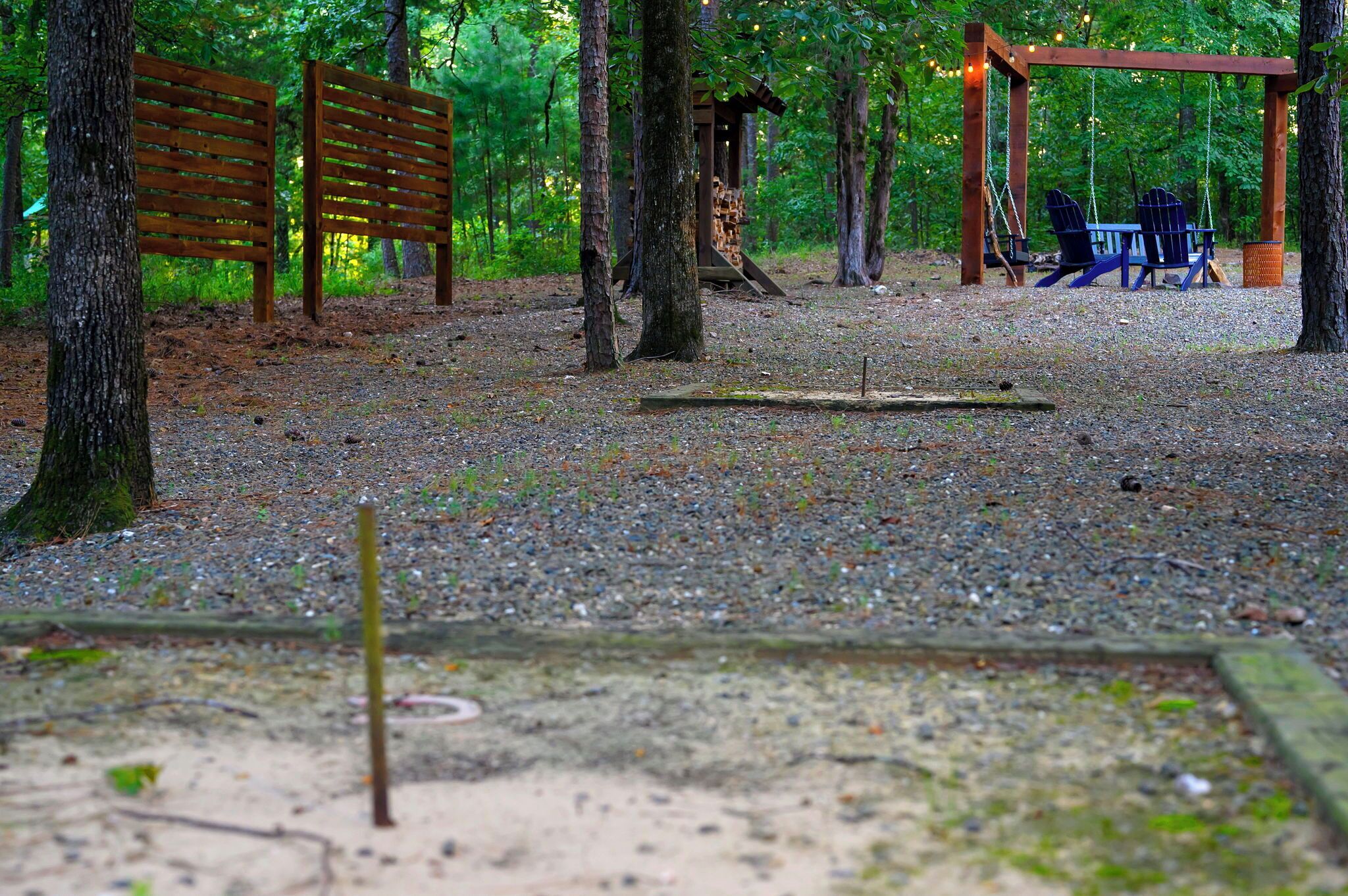 Un espace boisé avec un banc en bois, une balançoire et un espace de repos abrité.