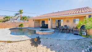 Una casa con piscina, muebles de patio y un pequeño jardín.