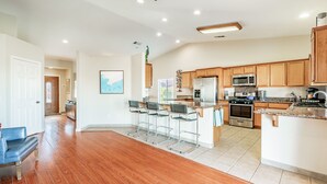 Una cocina amplia con armarios de madera, una isla central, taburetes de bar y electrodomésticos modernos.