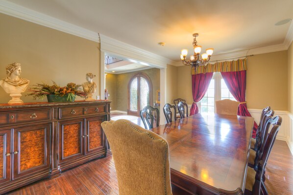 A formal dining room with a large wooden table, multiple chairs, a decorative cabinet, and a chandelier. - 7,000 Sqft At 'The Columns' Estate In South Tulsa (Tulsa)