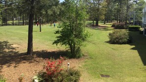 Ein Golfplatz mit gepflegtem Rasen, Bäumen und einigen spielenden Personen.