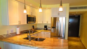 A modern kitchen with white cabinets, stainless steel appliances, and a marble countertop. - ★★★★★ Beachfront Newly Renovated Penthouse Washer/Dryer Perfect for Family WiFi (St. Thomas)