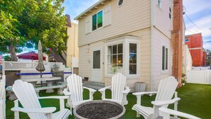 Eine Terrasse mit weißen Adirondack-Stühlen, einer Feuerstelle und einem Grillbereich.