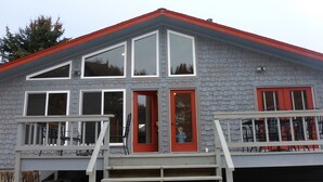 A two-story building with a red door and multiple windows. - Missouri Riverfront Bungalow Near Craig MT. (Cascade)