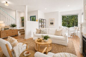 A modern living room with a white sofa, a round coffee table, and a fireplace.