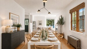 Ein Esszimmer mit einem langen Tisch, gedeckt für sechs Personen, umgeben von Holzsesseln.