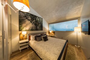 Relax in this serene bedroom with a large bed, bedside tables, and a wall-mounted TV.