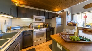 A modern kitchen with dark cabinets, stainless steel appliances, a granite countertop, and a wooden ceiling. - Rustic Modern Retreat! 3bed/2bath Close to Lifts (Crested Butte)