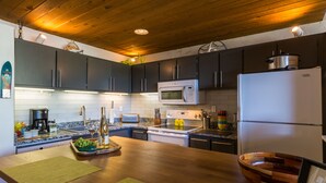 A modern kitchen with dark cabinets, a white refrigerator, a microwave, and a stove. - Rustic Modern Retreat! 3bed/2bath Close to Lifts (Crested Butte)