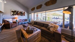 A living room with a large window, a sofa, a coffee table, and a lamp. - Rustic Modern Retreat! 3bed/2bath Close to Lifts (Crested Butte)