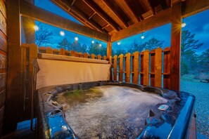 Ein Whirlpool im Freien mit einer Holzterrasse und einem Holenzaun.