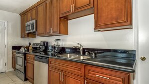 Una cucina con mobili in legno, elettrodomestici in acciaio inossidabile e un piano di lavoro nero.