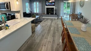 Een moderne keuken met witte kasten, een centraal eiland en een eetgedeelte met een houten tafel en stoelen.