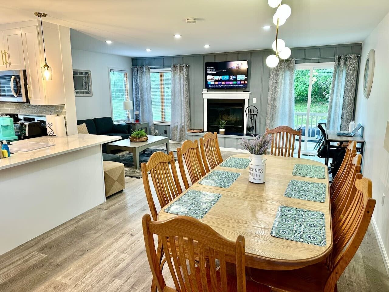 A modern kitchen with white cabinets, a built-in oven, and a dining area with a wooden table and chairs.