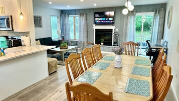 A modern kitchen with white cabinets, a built-in oven, and a dining area with a wooden table and chairs.