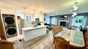 Een moderne keuken met een centraal eiland, een houten eettafel met stoelen en uitzicht op de omgeving.
