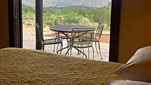 Une chambre avec un lit, une table et des chaises, donnant sur un canyon.