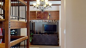 A living room with a wooden staircase, a chandelier, and a television. - Brian Head Platinum Studio, Pool-Jacuzzi, Ski-In/Out, , Sleeps 7,  Elevator (Brian Head)