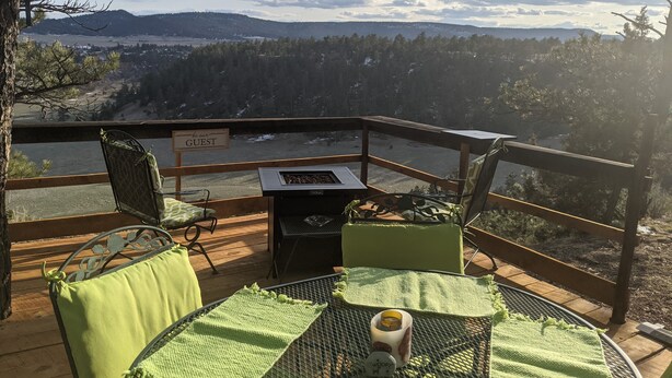 Eine Terrasse mit Sitzgelegenheiten, Grill und Blick auf eine bewaldete Landschaft.