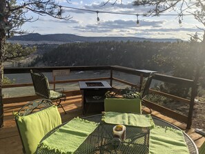 En terrass med utomhusmöbler, en grill och utsikt över ett skogslandskap.