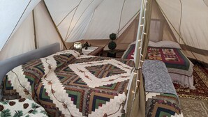 Ein Zelt mit Bett, einer Decke und einem kleinen Tisch mit Lampe.