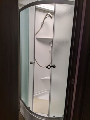 En duschkabin med en dörr av frostat glas, ett duschmunstycke och en handdukshängare.