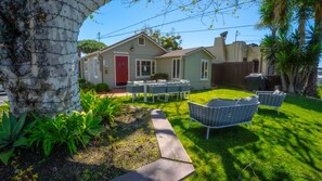 A house with a red door, a lawn, and outdoor furniture. - Green Beach House 500' to the Waves- Electric Vehicle Charger! (Laguna Beach)