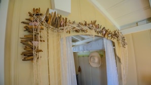 A room with a bed, a hanging hat, and a wall decorated with driftwood and netting. - Green Beach House 500' to the Waves- Electric Vehicle Charger! (Laguna Beach)
