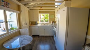 Cozinha compacta com mesa de mármore, geladeira e janela com vista para o exterior.