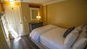 Un dormitorio con cama, lámparas de noche, cómoda, espejo y una puerta.