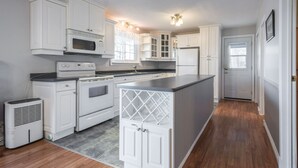 A modern kitchen with white cabinetry, a central island, and a built-in microwave.