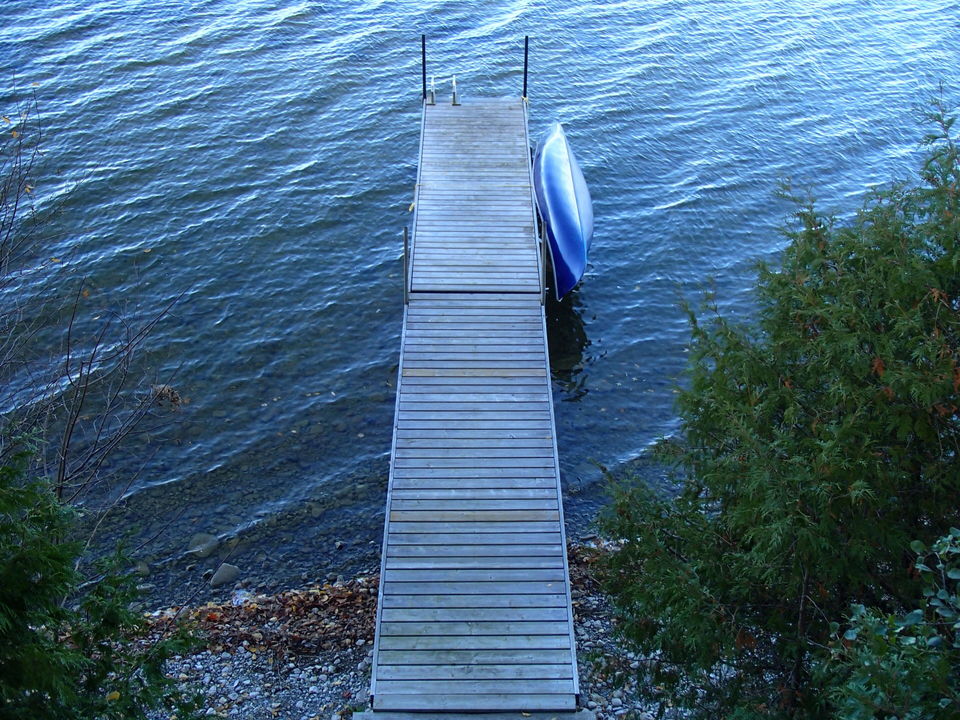 Un muelle de madera que se adentra en una masa de agua, con un bote amarrado.