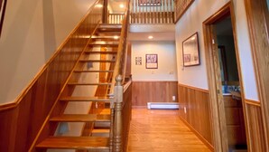 A wooden staircase with a handrail leading to a second-floor landing. - Luxurious Lakefront Living With Amenities close to Cooperstown (Richfield Springs)