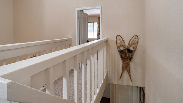 A staircase with white railings and a wall-mounted ski rack.