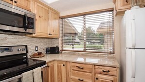 A modern kitchen with wooden cabinets, a microwave, a toaster, and a refrigerator.